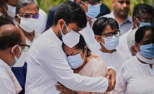 Anjali Rupani, the wife of former Chief Minister of Gujarat Vijay Rupani, who died in the Air India plane crash, is comforted by her son during a wreath-laying ceremony outside the mortuary of a hospital in Ahmedabad, India, Monday, June 16, 2025. (AP Photo/Rafiq Maqbool)