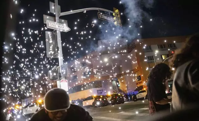 People take cover as a fire work explodes during a protest near the Metropolitan Detention Center in downtown Los Angeles, Sunday, June 8, 2025. (AP Photo/Ethan Swope)