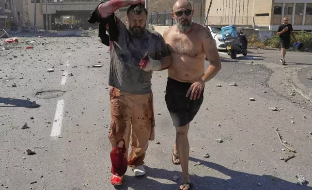 An injured man is evacuated from a site sturk by an Iranian missile in Haifa, Israel, on Friday, June 20, 2025. (AP Photo/Baz Ratner)