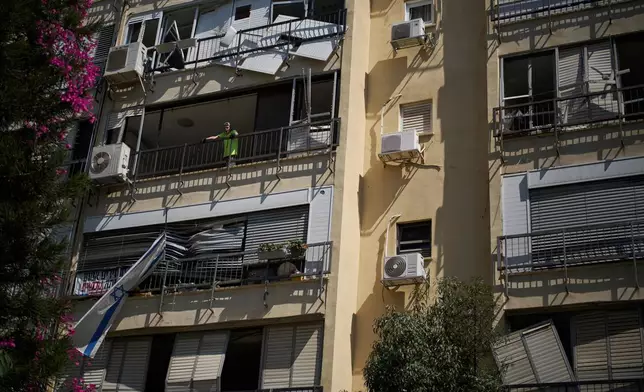 Yuval, 65, looks out from the window of his damaged apartment a day after of an Iranian missile strike in Ramat Gan, Israel, Friday, June 20, 2025. (AP Photo/Leo Correa)
