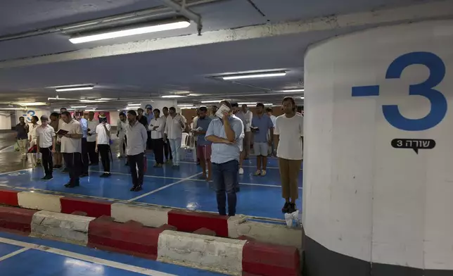 Jewish men attend a Shabbat prayer inside an underground parking for potential protection from missile strikes from Iran, in Tel Aviv, Israel, Friday, June 20, 2025. (AP Photo/Bernat Armangue)