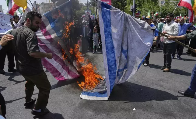Iranian protestors burn representations of the Israeli and U.S. flags during a protest to condemn Israeli attacks on multiple cities across Iran, after the Friday prayers ceremony in Tehran, Iran, Friday, June 20, 2025. (AP Photo/Vahid Salemi)