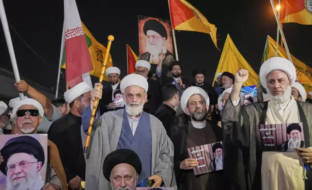 Iraqis Shiite clerics hold a portrait of Iran's Supreme Leader Ayatollah Ali Khamenei during a protest against Israeli attacks on multiple cities across Iran, at a bridge leading to the fortified Green Zone where the U.S. embassy is located in Baghdad, Iraq, Thursday, June 19, 2025. (AP Photo/Hadi Mizban)