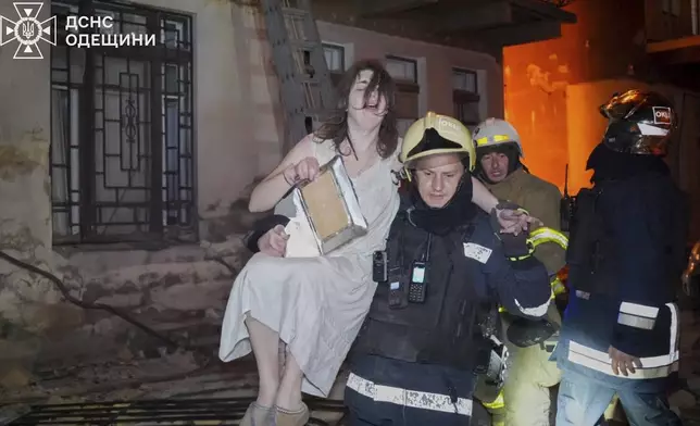 In this photo provided by the Ukrainian Emergency Service, firefighters evacuate a resident from a burning apartment building following Russia's massive air attack in Odesa, Ukraine, Friday, June 20, 2025. (Ukrainian Emergency Service via AP)