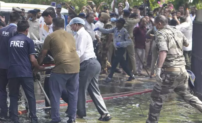 Rescuers carry the body of a victim of an airplane that crashed in India's northwestern city of Ahmedabad in Gujarat state, Thursday, June12, 2025. (AP Photo/Ajit Solanki)