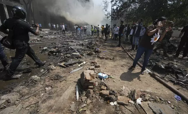 Peple are seen at the site of an airplane that crashed in India's northwestern city of Ahmedabad in Gujarat state, Thursday, June 12, 2025. (AP Photo/Ajit Solanki)