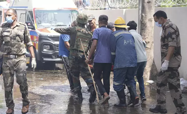 Rescuers carry the body of a victim from the site of an airplane that crashed in India's northwestern city of Ahmedabad in Gujarat state, Thursday, June 12, 2025. (AP Photo/Ajit Solanki)