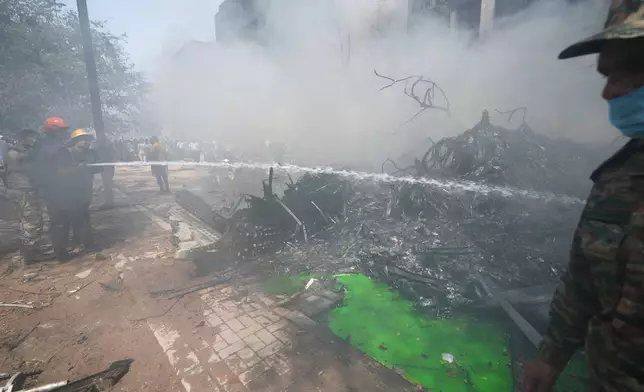Fire fighters spray water at the site of an airplane that crashed in India's northwestern city of Ahmedabad in Gujarat state, Thursday, June12, 2025. (AP Photo/Ajit Solanki)