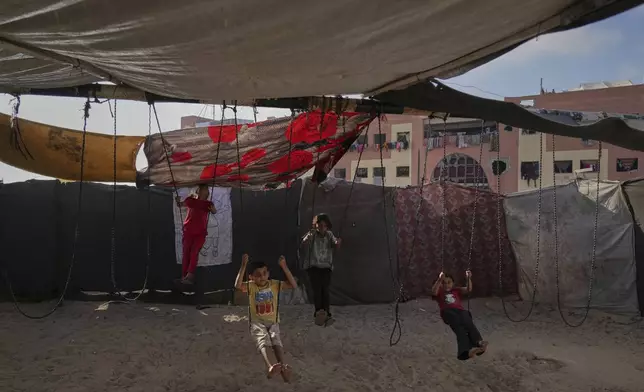 Displaced Palestinian children play on swings at a makeshift tent camp in Khan Younis, Gaza, on Wednesday, June 4, 2025. (AP Photo/Abdel Kareem Hana)