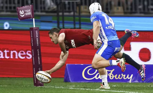 Tomos Williams of the British &amp; Irish Lions is airborne as he scores a try as Western Forces' Mac Grealy watches during their rugby match against the Western Force in Perth, Australia, Saturday, June 28, 2025. (AP Photo/Trevor Collens)
