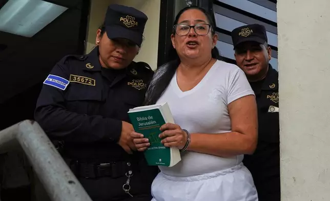 Human rights lawyer Ruth Eleonora Lopez, handcuffed, holds a bible as police escort her out of her court hearing in San Salvador, El Salvador, Wednesday, June 4, 2025. (AP Photo/Salvador Melendez)