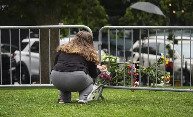 Alexandra Posnock, who moved a month ago from Skokie, Ill., to Boulder, Colo., places a bouquet of flowers along a makeshift barrier outside of the Boulder County, Colo., courthouse after Sunday's attack, Monday, June 2, 2025, in Boulder, Colo. (AP Photo/David Zalubowski)