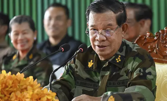 In this photo released by Agence Kampuchea Press (AKP), Cambodian Senate President Hun Sen, right, delivers a speech during his visit to Oddar Meanchey province, near Cambodia-Thailand border of northern province of Cambodia, Thursday, June 26, 2025. (AKP via AP)