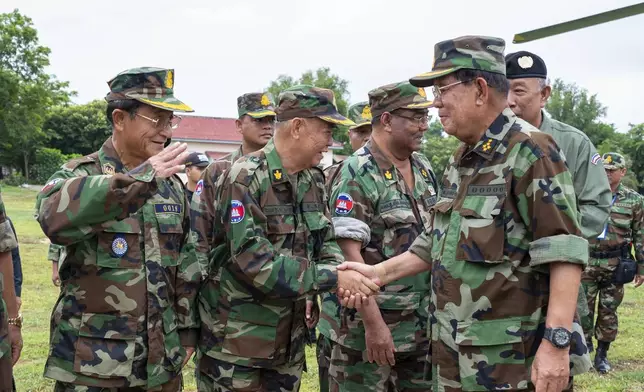 In this photo released by Agence Kampuchea Press (AKP), Cambodian Senate President Hun Sen, right, greets with his top general officers during his visit to Oddar Meanchey province, near Cambodia-Thailand border of northern province of Cambodia, Thursday, June 26, 2025. (AKP via AP)
