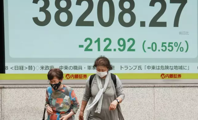 People walk in front of an electronic stock board showing Japan's Nikkei index at a securities firm Thursday, June 12, 2025, in Tokyo. (AP Photo/Eugene Hoshiko)