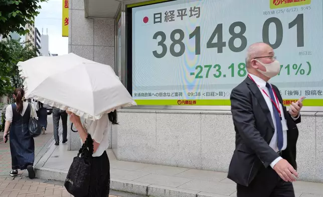 People walk in front of an electronic stock board showing Japan's Nikkei index at a securities firm Thursday, June 12, 2025, in Tokyo. (AP Photo/Eugene Hoshiko)