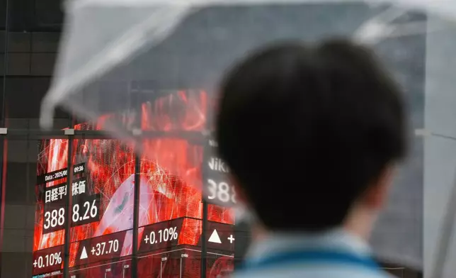 A person stands in front of an electronic stock board showing Japan's Nikkei index at a securities firm Wednesday, June 25, 2025, in Tokyo. (AP Photo/Eugene Hoshiko)