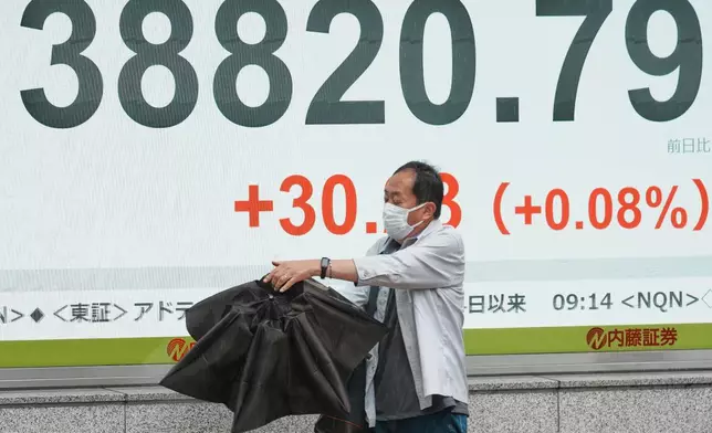 A person walks in front of an electronic stock board showing Japan's Nikkei index at a securities firm Wednesday, June 25, 2025, in Tokyo. (AP Photo/Eugene Hoshiko)