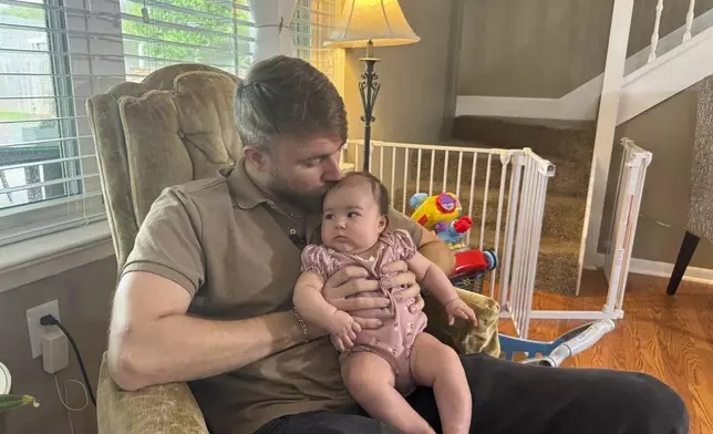 U.S. Marine Corps veteran Adrian Clouatre holds his 3-month-old daughter Lyn at their home in Baton Rouge, La. on Tuesday, June 17, 2025. (AP Photo/Jack Brook)