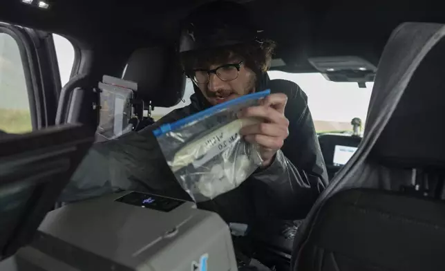 Tony Illenden turns to place a bag of hail he collected into a cooler in the backseat of the Northern Illinois University's Husky Hail Hunter during a Project ICECHIP operation Friday, June 6, 2025, in Levelland, Texas. (AP Photo/Carolyn Kaster)