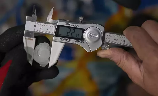 Jake Sorber measures hail in the Walmart parking lot during a Project ICECHIP operation Friday, June 6, 2025, in Levelland, Texas. (AP Photo/Carolyn Kaster)