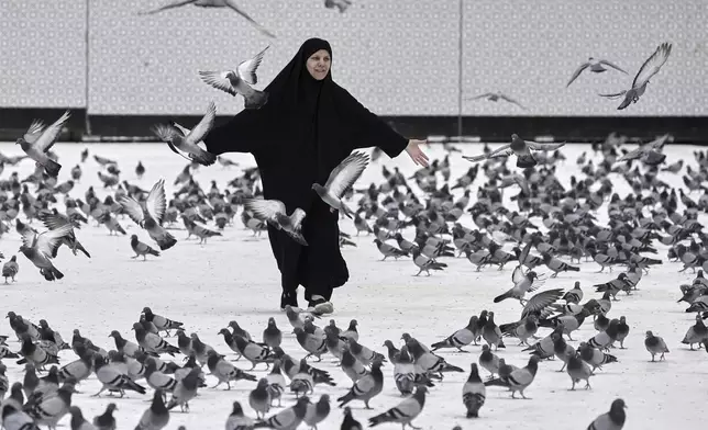 A Muslim pilgrim plays with pigeons outside the Grand Mosque during the annual hajj pilgrimage in Mecca, Saudi Arabia, Tuesday, June 3, 2025. (AP Photo/Amr Nabil)