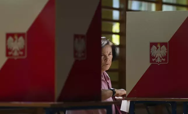 A woman prepares to cast her vote during the presidential election runoff in Warsaw, Poland, Sunday, June 1, 2025. (AP Photo/Petr David Josek)