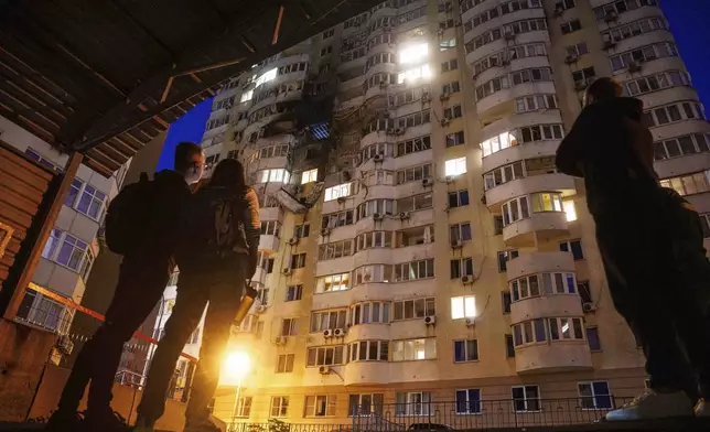 People look at a residential multi-storey building damaged after a Russian drone strike on Kyiv, Ukraine, on Friday, June 6, 2025. (AP Photo/Evgeniy Maloletka)