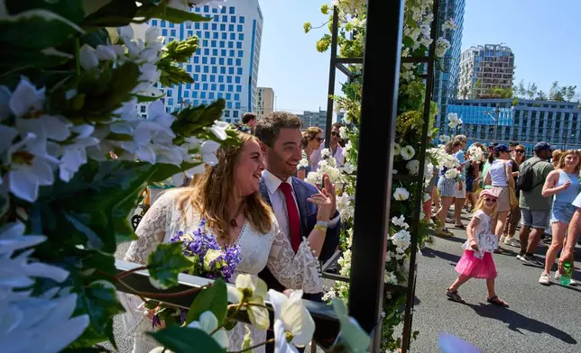 Zuzana Lisowska and Yuri Iozzelli pose for photos after getting married on a highway bypass, as the Dutch capital celebrates its 750th anniversary with weddings, music and other events on the A10 ring road in Amsterdam, Netherlands, Saturday, June 21, 2025. (AP Photo/Peter Dejong)
