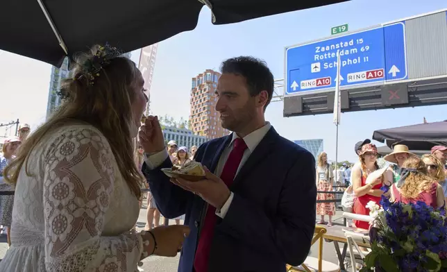 Zuzana Lisowska and Yuri Iozzelli get married on a highway bypass, as the Dutch capital celebrates its 750th anniversary with weddings, music and other events on the A10 ring road in Amsterdam, Netherlands, Saturday, June 21, 2025. (AP Photo/Peter Dejong)