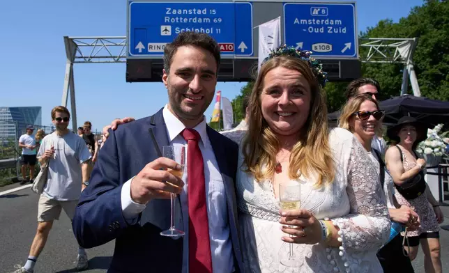 Zuzana Lisowska and Yuri Iozzelli celebrate after getting married on a highway bypass as the Dutch capital celebrates its 750th anniversary with weddings, music and other events on the A10 ring road in Amsterdam, Netherlands, Saturday, June 21, 2025. (AP Photo/Peter Dejong)