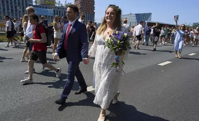 Zuzana Lisowska and Yuri Iozzelli celebrate after getting married on a highway bypass, as the Dutch capital celebrates its 750th anniversary with weddings, music and other events on the A10 ring road in Amsterdam, Netherlands, Saturday, June 21, 2025. (AP Photo/Peter Dejong)