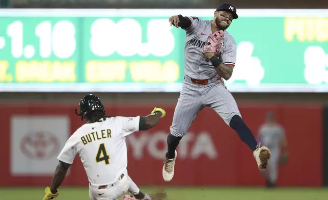 Minnesota Twins shortstop Carlos Correa, right, throws to first for the double play against the Athletics during the ninth inning of a baseball game Monday, June 2, 2025, in West Sacramento, Calif. (AP Photo/Scott Marshall)