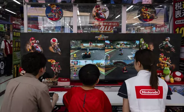 Staff and members of the public try the Nintendo Switch 2 during a launch event at an electronics retailer in Tokyo, Thursday, June 5, 2025. (AP Photo/Louise Delmotte)