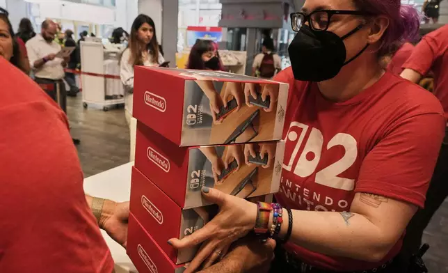 A stack of the Nintendo Switch 2 devices are handed off at the Nintendo store in New York's Rockefeller Center, Thursday, June 5, 2025. (AP Photo/Richard Drew)
