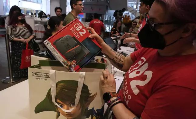 A Nintendo store cashier places a Switch 2 in a bag for a customer at the Nintendo store in New York's Rockefeller Center, Thursday, June 5, 2025. (AP Photo/Richard Drew)