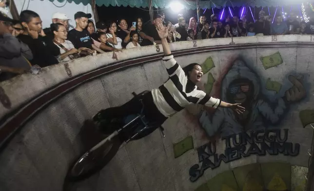 Sri Wahyuni, also known as Ayu, performs in the "wall of death", locally known as "tong setan" or satan's barrel, at a fairground in Medan, North Sumatra, Indonesia, May 10, 2025. (AP Photo/Binsar Bakkara)