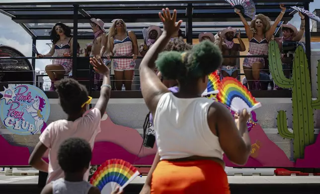 Children wave as a parade float passes during the Kentuckiana Pride Parade on Saturday, June 21, 2025, in Louisville, Ky. (AP Photo/Jon Cherry)