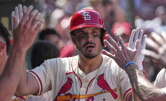 St. Louis Cardinals' Nolan Arenado is congratulated by teammates in the dugout after hitting a solo home run during the ninth inning of a baseball game against the Cincinnati Reds Saturday, June 21, 2025, in St. Louis. (AP Photo/Jeff Roberson)
