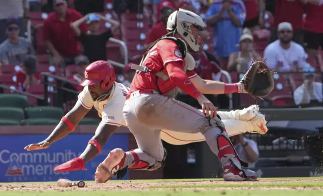St. Louis Cardinals' Jordan Walker, left, scores the game-winning run past Cincinnati Reds catcher Tyler Stephenson in the 11th inning of a baseball game Saturday, June 21, 2025, in St. Louis. (AP Photo/Jeff Roberson)
