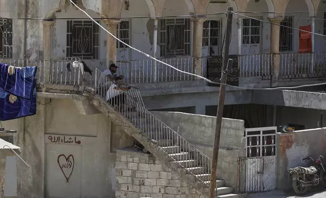 Residents sit outside their house in the Beit Jin village, southern Syria, where Israeli troops made a pre-dawn raid, arresting several alleged members of Hamas, Thursday, June 12, 2025. (AP Photo/Omar Sanadiki)