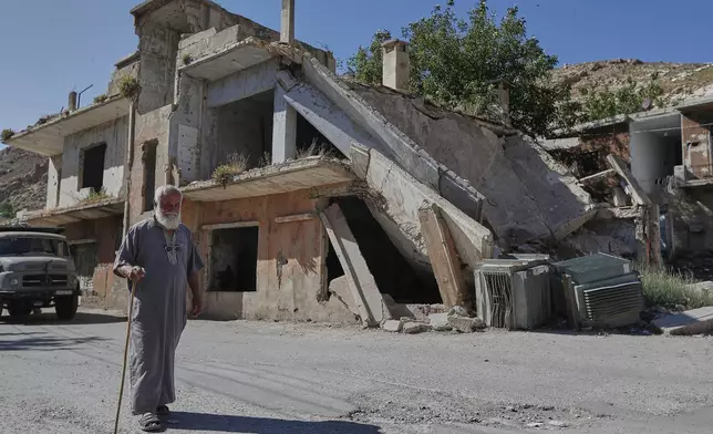A man passes a house destroyed during the Syrian civil war at Beit Jin village, southern Syria, where Israeli troops made a pre-dawn raid, Thursday, June 12, 2025. (AP Photo/Omar Sanadiki)