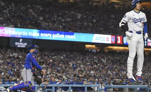Los Angeles Dodgers' Shohei Ohtani, right, jumps after taking a strike as New York Mets catcher Luis Torrens kneels at the plate during the fifth inning of a baseball game Wednesday, June 4, 2025, in Los Angeles. (AP Photo/Mark J. Terrill)