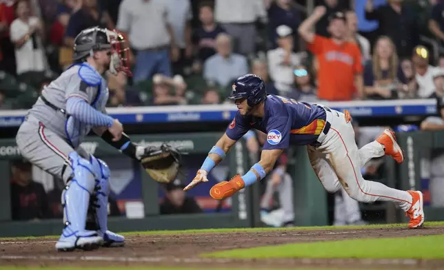 Houston Astros' Jeremy Peña, right, dives toward home plate to score as Minnesota Twins catcher Christian Vázquez waits for the throw during the ninth inning of a baseball game Sunday, June 15, 2025, in Houston. (AP Photo/David J. Phillip)