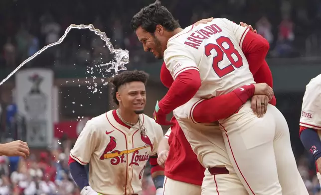St. Louis Cardinals' Nolan Arenado (28) is congratulated by teammates after hitting a walk-off single to defeat the Los Angeles Dodgers in a baseball game Saturday, June 7, 2025, in St. Louis. (AP Photo/Jeff Roberson)