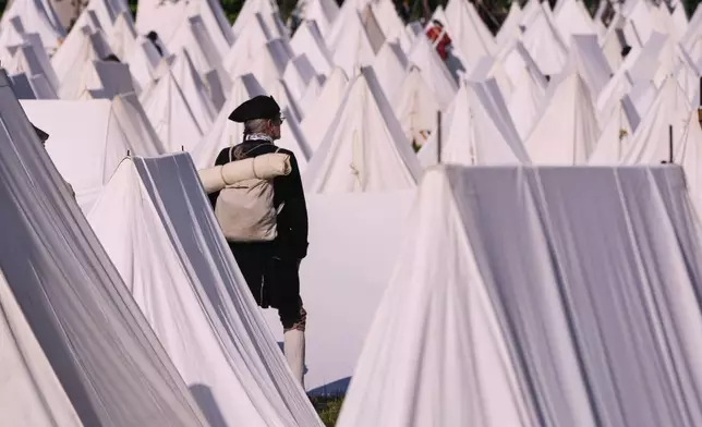 Ed Knight, of Manchester, Vt., who portrays a Colonial soldier, stands among the encampment tents during a reenactment in celebration of the 250th anniversary of the Battle of Bunker Hill, Saturday, June 21, 2025, in Gloucester, Mass. (AP Photo/Charles Krupa)