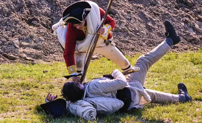 A Colonial soldier is knocked to the ground by a British soldier during a reenactment in celebration of the 250th anniversary of the Battle of Bunker Hill, Saturday, June 21, 2025, in Gloucester, Mass. (AP Photo/Charles Krupa)
