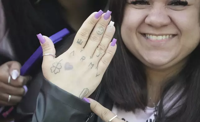 Daiane Matos from Brazil, 37, shows her hand as she waits for arrival of K-pop band BTS members Jimin and Jung Kook in Yeoncheon, South Korea, Wednesday, June 11, 2025. (AP Photo/Lee Jin-man)