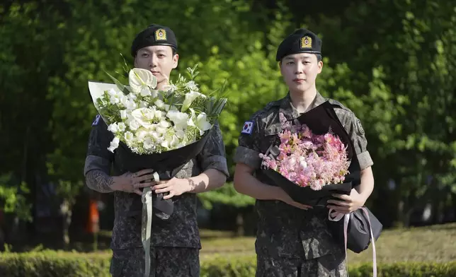 K-pop band BTS members Jimin, right, and Jung Kook hold bouquets after being discharged from a mandatory military service in Yeoncheon, South Korea, Wednesday, June 11, 2025. (AP Photo/Lee Jin-man)