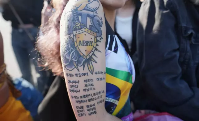 Anaisa Silva, from Portugal, a fan of K-pop band BTS shows a tattoo as they wait for K-pop band BTS members Jimin and Jung Kook in Yeoncheon, South Korea, Wednesday, June 11, 2025. (AP Photo/Lee Jin-man)